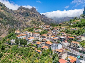 A hillside village with terraced houses, a main road, and mountains in the background. - Cora o da Madeira - Quebrada by Homie (Camara de Lobos)