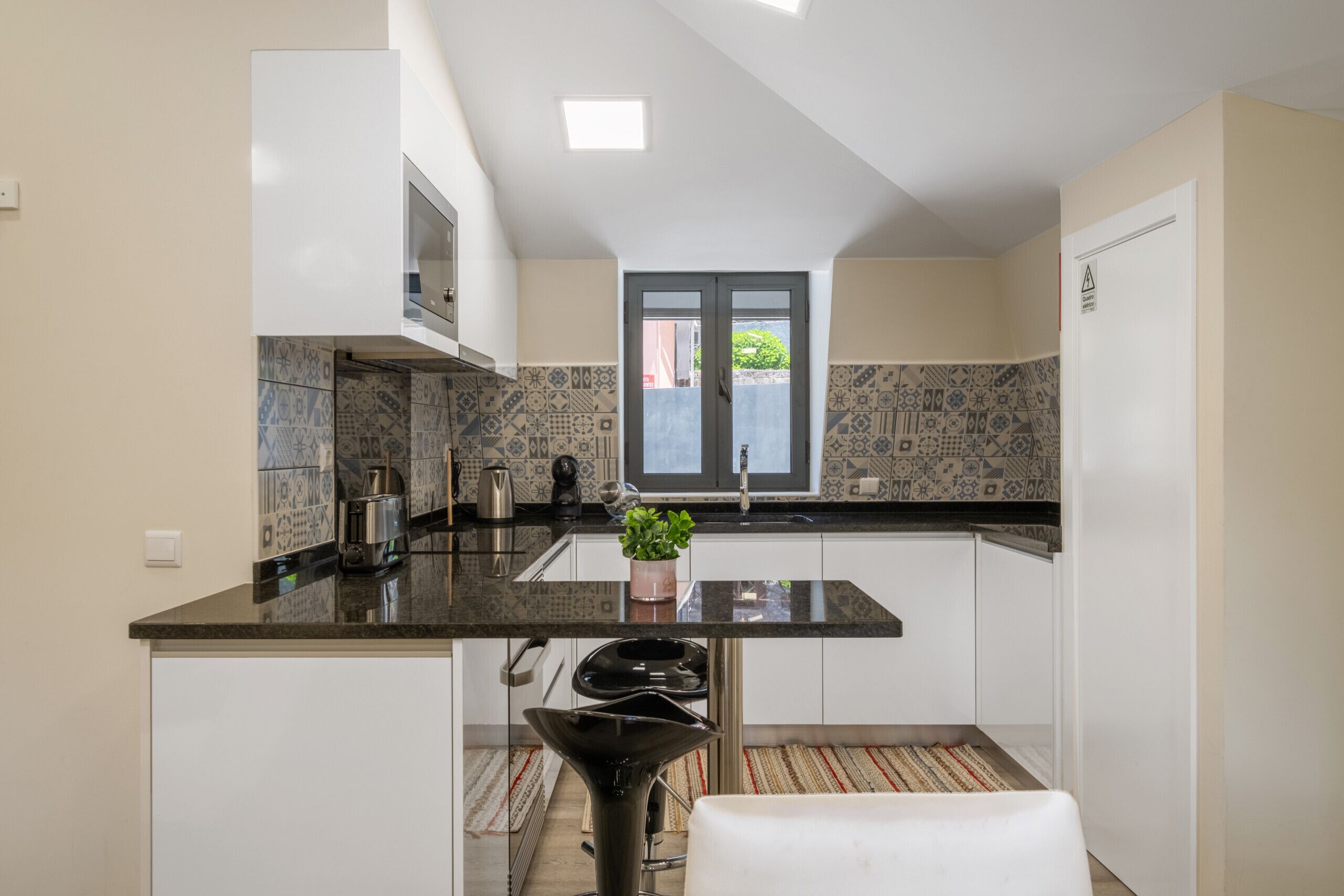 A modern kitchen with white cabinets, a black countertop, and patterned tiles.
