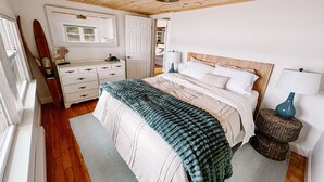 A bedroom with a wooden ceiling, a bed with white bedding, a dresser, a lamp, and a surfboard on the wall. - Hideaway in Higley Flow! (Colton)