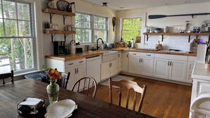 A kitchen with white cabinets, wooden countertops, and a dining table with chairs. - Hideaway in Higley Flow! (Colton)