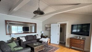 A living room with a sofa, coffee table, TV, and a door leading to another room. - Hideaway in Higley Flow! (Colton)