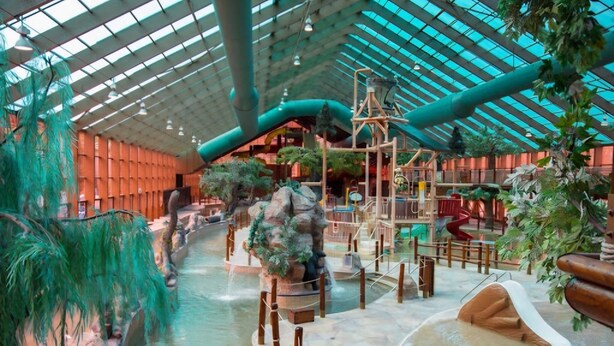 Un parc aquatique intérieur doté d’un toit en verre, de toboggans et de formations rocheuses artificielles.