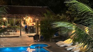 Una piscina de diseño curvo, rodeada de tumbonas y palmeras.