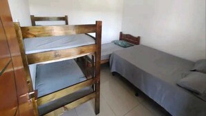 Un alojamiento pequeño de una sola habitación con una cama individual, una litera y un armario de madera.