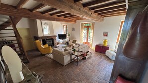 A spacious living room with a fireplace, a yellow armchair, and a sofa. - Entire vacation home in Burgundy style: Longère des Daubénys (Precy-sur-Vrin)