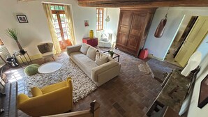A spacious living area with a sofa, yellow armchair, and a coffee table. There is a wooden cabinet and a red chair in the background. - Entire vacation home in Burgundy style: Longère des Daubénys (Precy-sur-Vrin)