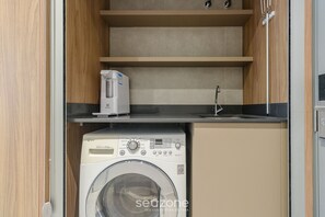 A compact kitchen with a washing machine, a toaster, and a sink. - Modern and Fully Equipped Apartments Just Minutes From Lagoa da Conceicao and the Beach - VTD (Florianópolis)