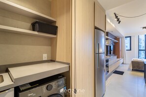 A modern kitchen with a built-in washer, a refrigerator, and a dining area with a table and chairs. - Modern and Fully Equipped Apartments Just Minutes From Lagoa da Conceicao and the Beach - VTD (Florianópolis)