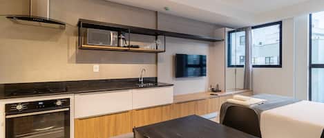 Une cuisine moderne dotée d’appareils électroménagers intégrés, un coin repas et une grande fenêtre offrant une vue sur la ville.