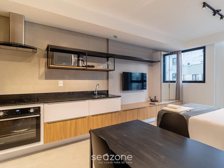 A modern kitchen with built-in appliances, a dining area, and a large window providing a view of the city.