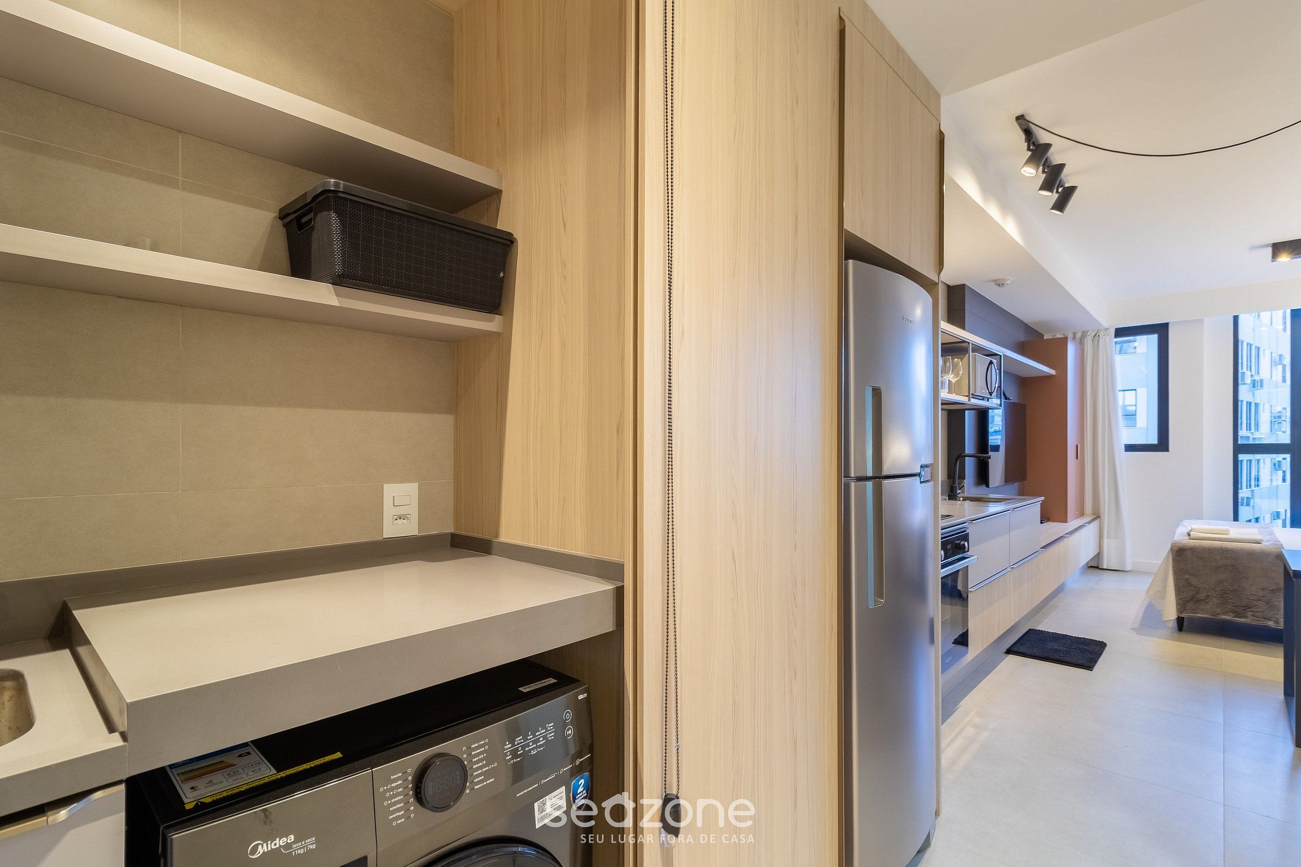 Una cocina moderna con lavadora integrada, un refrigerador y un comedor con mesa y sillas.
