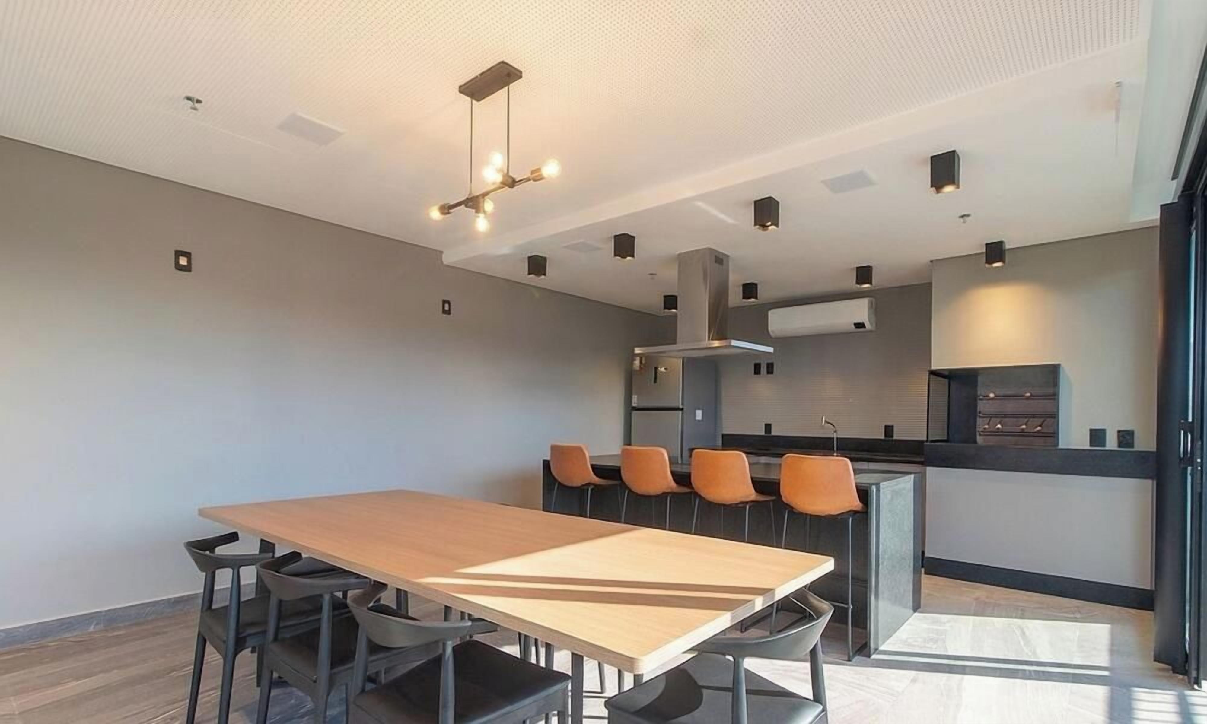 Una cocina moderna con una isla central, una mesa de comedor con sillas e iluminación colgante.