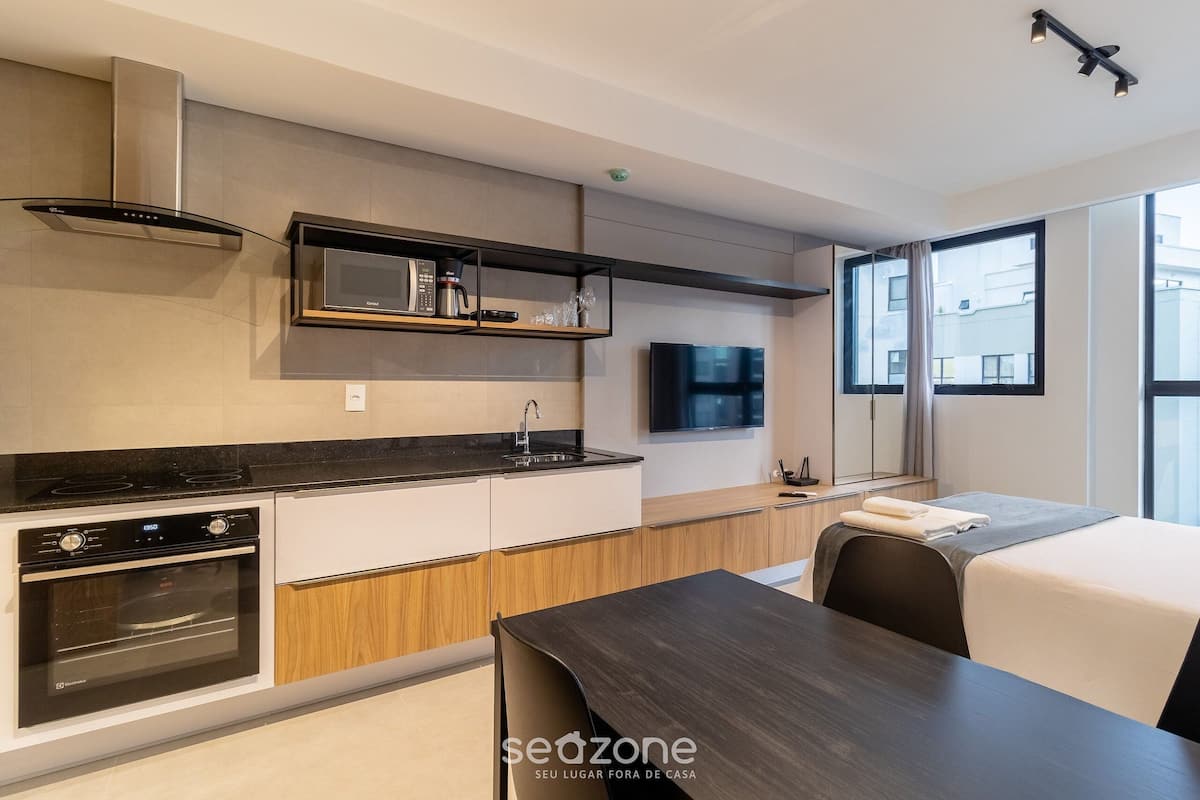 A modern kitchen with built-in appliances, a dining area, and a large window providing a view of the city.