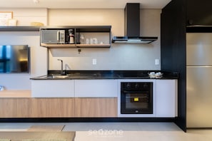 Una cocina moderna con microondas integrado, horno y electrodomésticos de acero inoxidable.