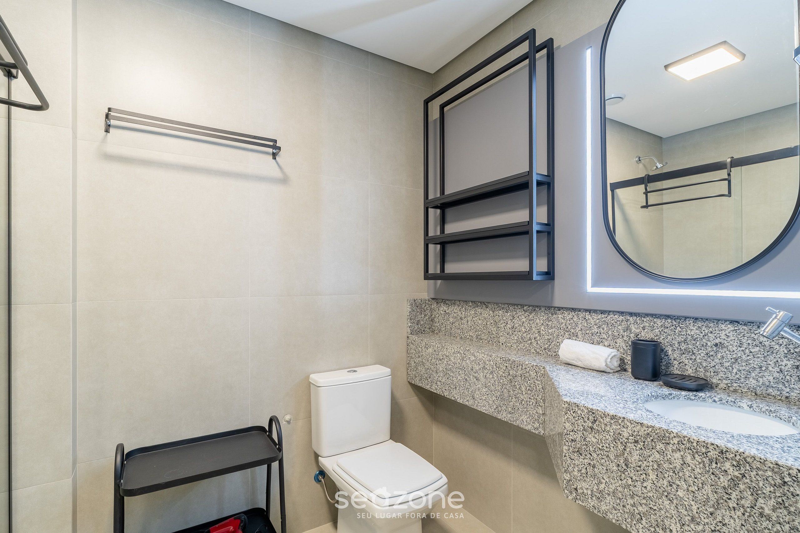 A modern bathroom with a toilet, a sink, a mirror, and a towel rack.