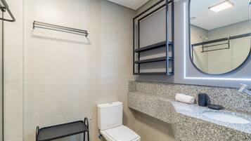 A modern bathroom with a toilet, a sink, a mirror, and a towel rack.