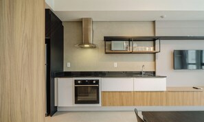 A modern kitchen with a built-in oven, microwave, and a stainless steel range hood. - Modern and Fully Equipped Apartments Just Minutes From Lagoa da Conceicao and the Beach - VTD (Florianópolis)