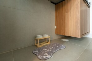 A bathroom with a wooden cabinet, a small wooden stool with bowls, and a pet-friendly mat. - Modern and Fully Equipped Apartments Just Minutes From Lagoa da Conceicao and the Beach - VTD (Florianópolis)