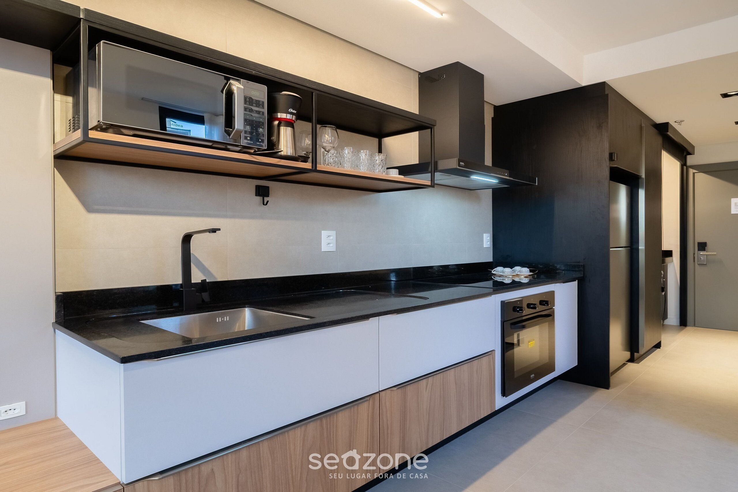 A modern kitchen with a black countertop, stainless steel appliances, and a built-in oven.