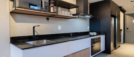 A modern kitchen with a black countertop, stainless steel appliances, and a built-in oven.