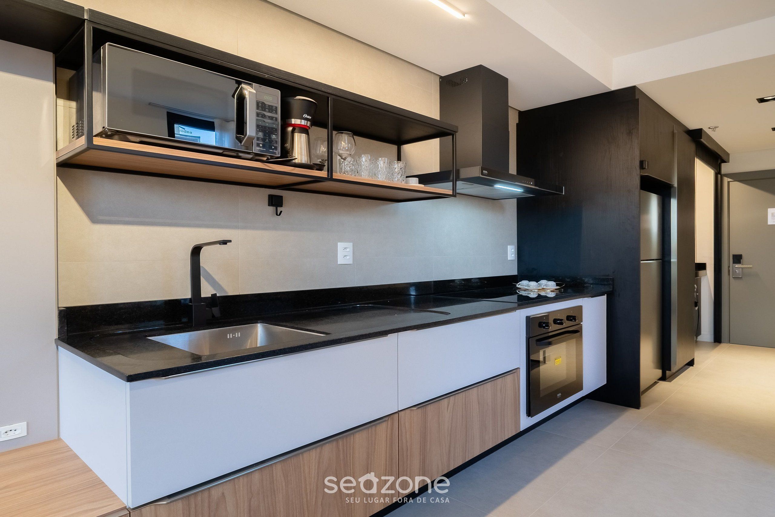 A modern kitchen with a black countertop, stainless steel appliances, and a built-in oven.