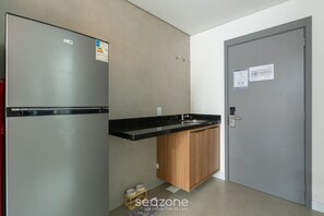 A kitchen with a stainless steel refrigerator, a wooden cabinet, and a grey door with a lock. - Modern and Fully Equipped Apartments Just Minutes From Lagoa da Conceicao and the Beach - VTD (Florianópolis)