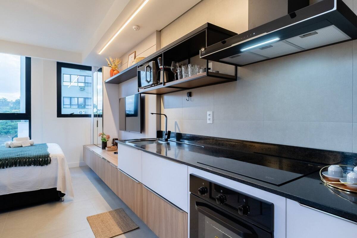 A modern kitchen with a black countertop, built-in oven, and a window overlooking a cityscape.