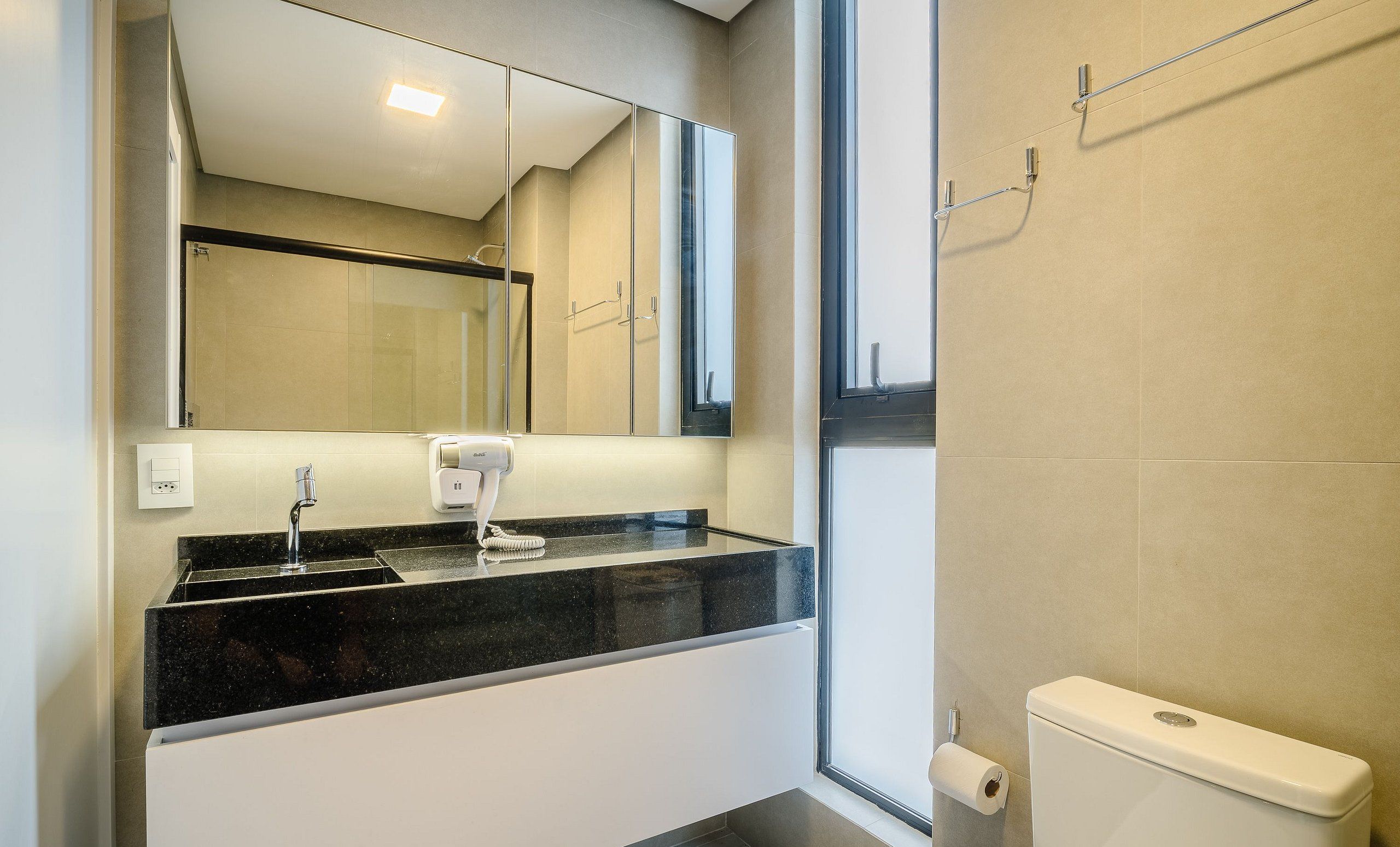 A bathroom with a mirror, sink, and toilet.