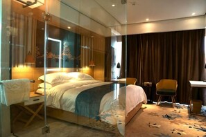 Une chambre d’hôtel moderne avec une cloison en verre, un lit, un bureau et une chaise.