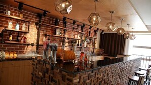 A bar area with brick walls, shelves with bottles, and hanging lights. - M-one Hotel (Guiyang)