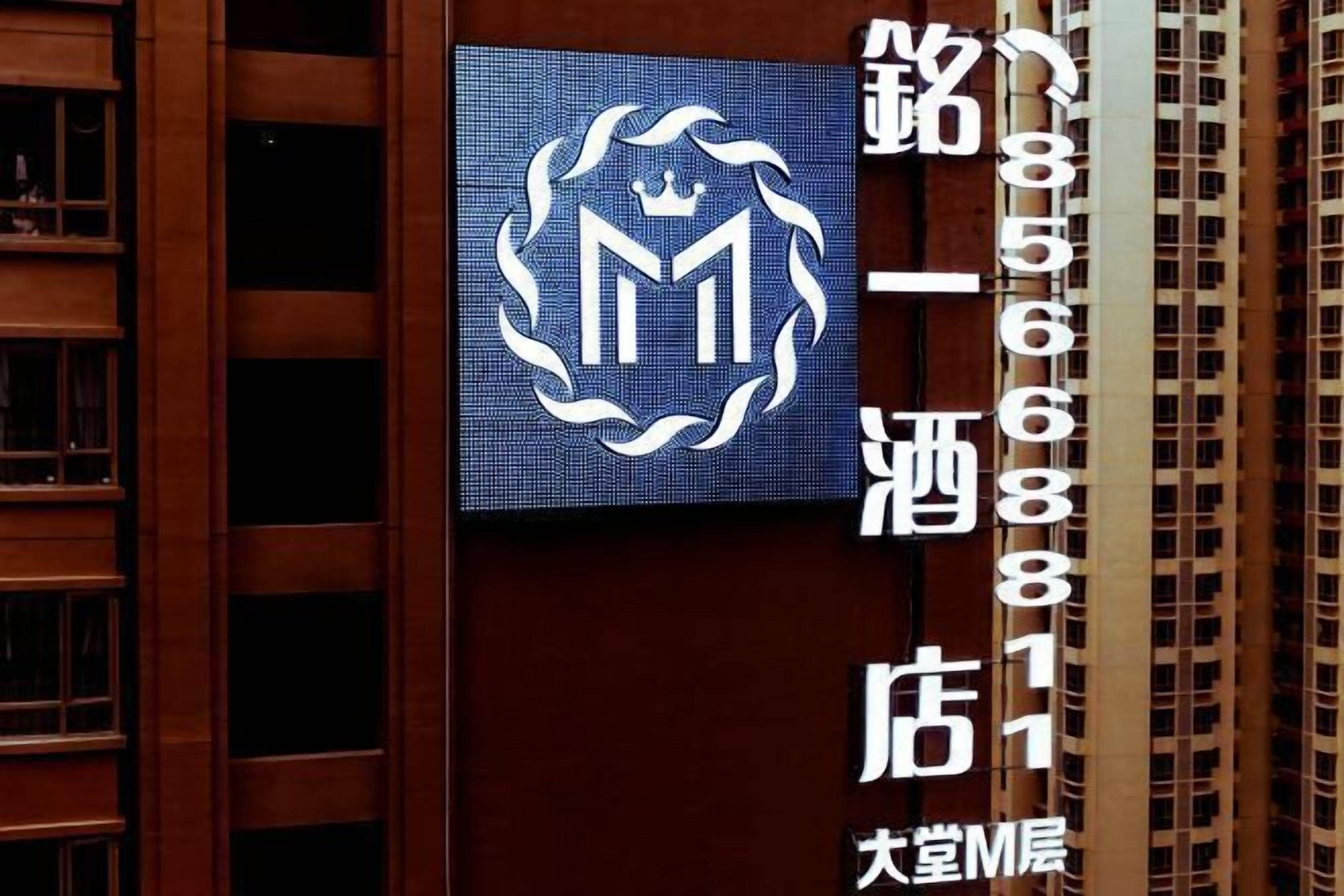 A hotel sign with a logo and contact number.