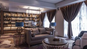 A modern living room with a sofa, round coffee table, and a bookshelf. - M-one Hotel (Guiyang)
