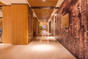 A hotel corridor with a wooden partition on the left, a cityscape mural on the right, and a polished floor. - M-one Hotel (Guiyang)