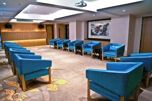 A conference room with rows of blue chairs, a carpet with a floral pattern, and a wooden panel wall. - M-one Hotel (Guiyang)