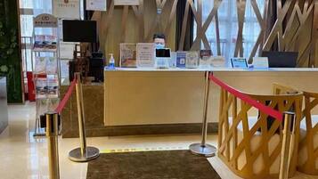 A reception desk with a check-in counter, a red rope barrier, and a decorative wooden partition.