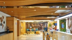 A modern hotel lobby with a wooden ceiling, a reception desk, and a seating area with a sofa and chairs. - M-one Hotel (Guiyang)
