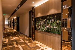 A hotel corridor with patterned carpet, wooden paneling, and a wall-mounted display. - M-one Hotel (Guiyang)