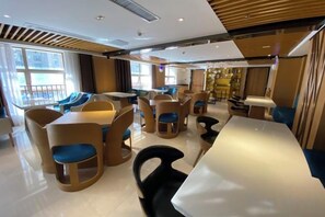 A modern dining area with tables and chairs, large windows, and a view of the outside. - M-one Hotel (Guiyang)