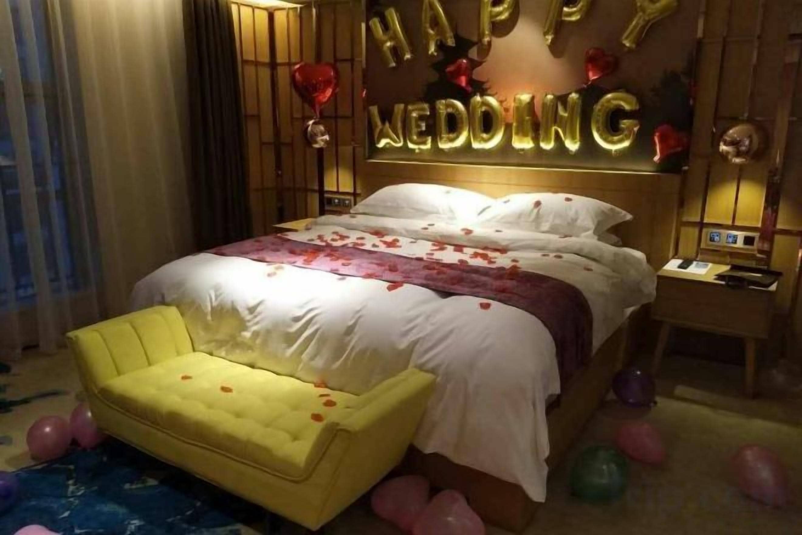 A hotel room with a bed, a bedside table, and a yellow armchair.
