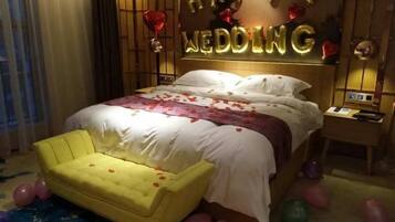 A hotel room with a bed, a bedside table, and a yellow armchair.