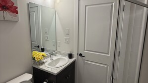 A modern bathroom with a toilet, sink, and shower. - New suite in a great location. Central for shopping, restaurants and commuting. (Regina)