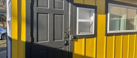 A yellow building with a black door and a window.