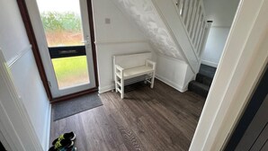 A room with a wooden floor, a white bench, a radiator, and a door leading outside.