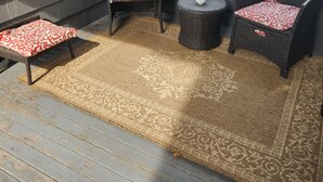 A covered patio area with wicker furniture and a patterned rug. - Coastal Charm  – Walk to Beach or Train! (Swampscott)