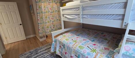 Ein Schlafzimmer mit Etagenbett, einem gemusterten Bettbezug, einem Deckenventilator und einer Tür.