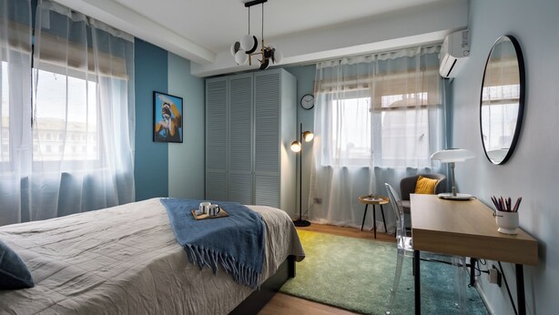 Une chambre à coucher avec un lit, un bureau, une chaise, une lampe et un miroir.