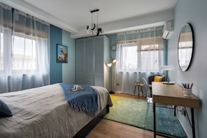 Une chambre à coucher avec un lit, un bureau, une chaise, une lampe et un miroir.