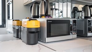 Un espace cuisine équipé de plusieurs machines à café, dont un four à micro-ondes Sharp et des machines à expresso.