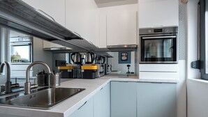 Une cuisine moderne dotée d’appareils électroménagers en acier inoxydable, d’un four encastré et d’un grand îlot central avec un évier.