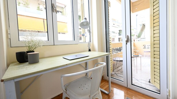 A room with a desk, chair, and a view of the outside balcony.